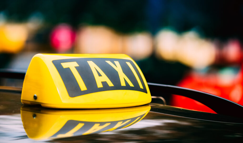 Panneau de taxi jaune sur le toit d'une voiture.