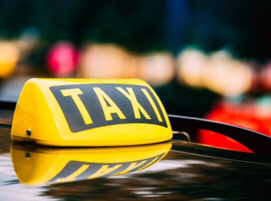 Panneau de taxi jaune sur le toit d'une voiture.