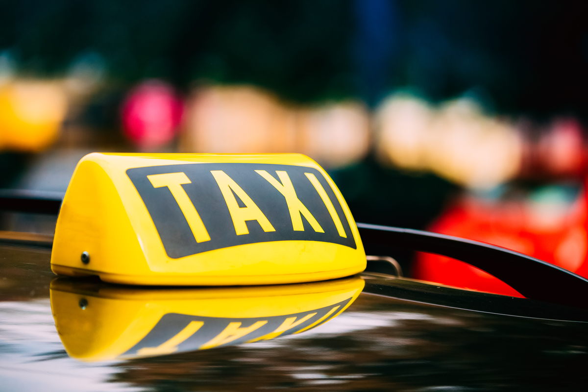 Panneau de taxi jaune sur le toit d'une voiture.